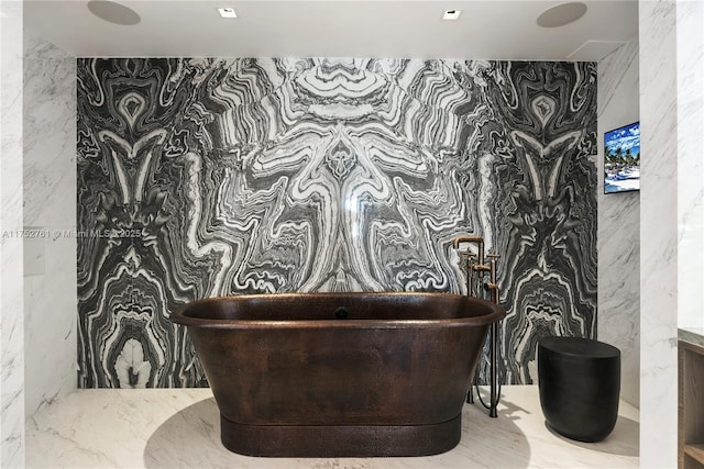 bathroom with stone wall and a freestanding bath