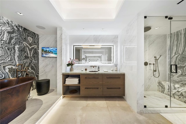 full bath featuring a freestanding tub, a marble finish shower, tile walls, and vanity