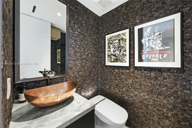 bathroom with toilet, vanity, and visible vents