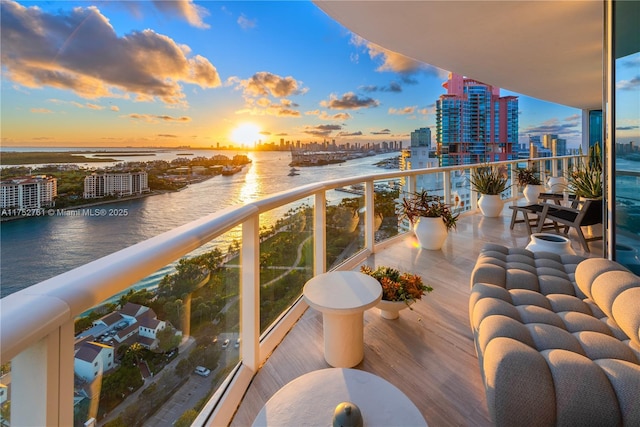 balcony at dusk featuring a view of city and a water view