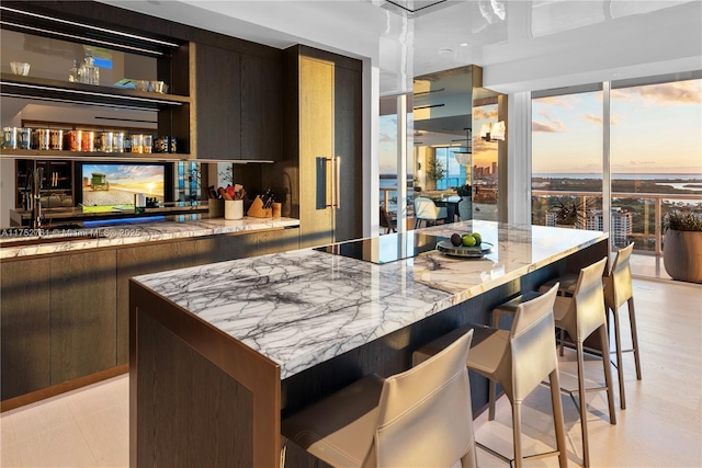 100 S Pointe Dr Unit 2803, Miami Beach, FL 33139 - kitchen featuring a kitchen breakfast bar, black electric cooktop, light stone countertops, a kitchen island, and modern cabinets