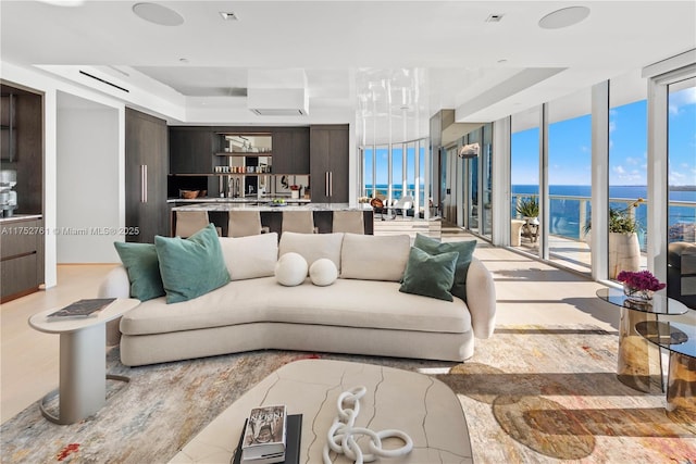 living area featuring a raised ceiling, floor to ceiling windows, and a water view