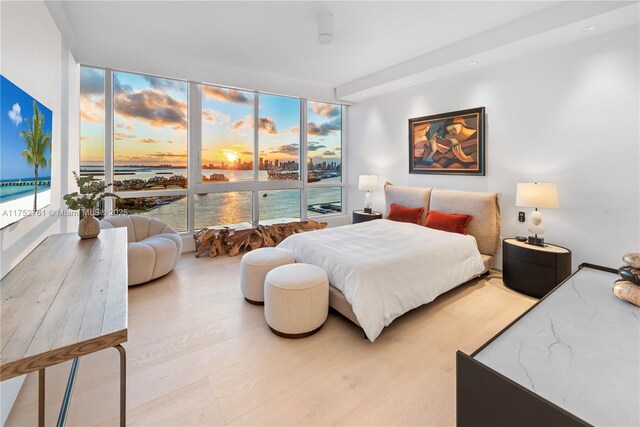 bedroom with a water view, expansive windows, and wood finished floors