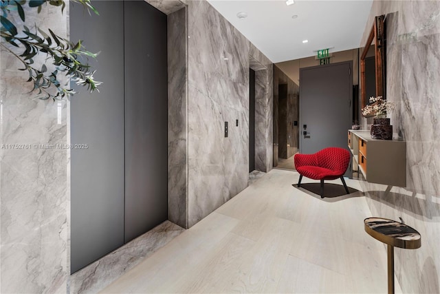 hallway featuring elevator and tile walls