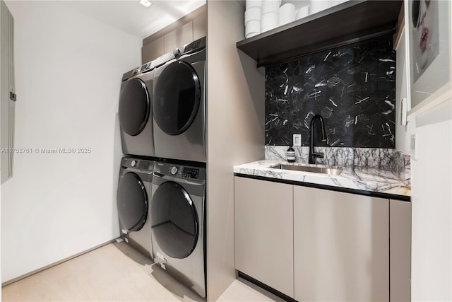 laundry area featuring stacked washer / drying machine, laundry area, and a sink