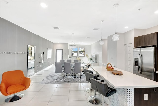 kitchen featuring stainless steel fridge, a kitchen island, open floor plan, light countertops, and light tile patterned flooring