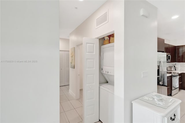 laundry room featuring laundry area, visible vents, stacked washer and clothes dryer, light tile patterned flooring, and recessed lighting