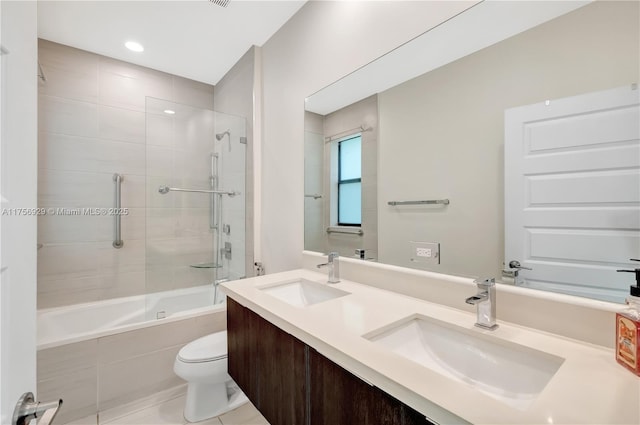 bathroom with a sink, tiled shower / bath combo, toilet, and double vanity