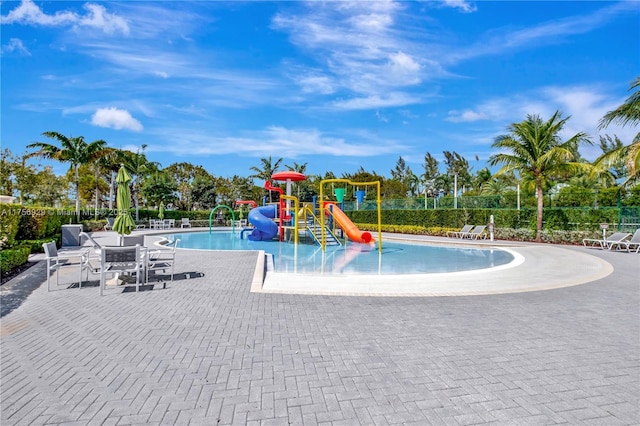 community play area with a patio, a water play area, a community pool, and fence