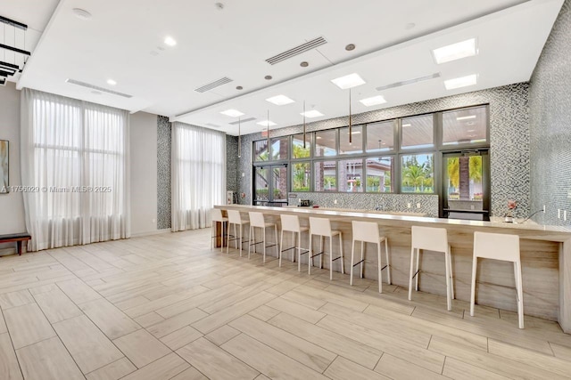 interior space with a healthy amount of sunlight, wood finish floors, visible vents, and decorative backsplash