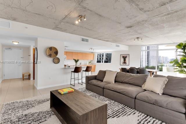 living room with light tile patterned flooring, visible vents, and baseboards