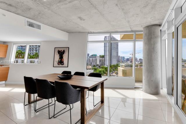 dining area with light tile patterned floors, baseboards, visible vents, and a city view