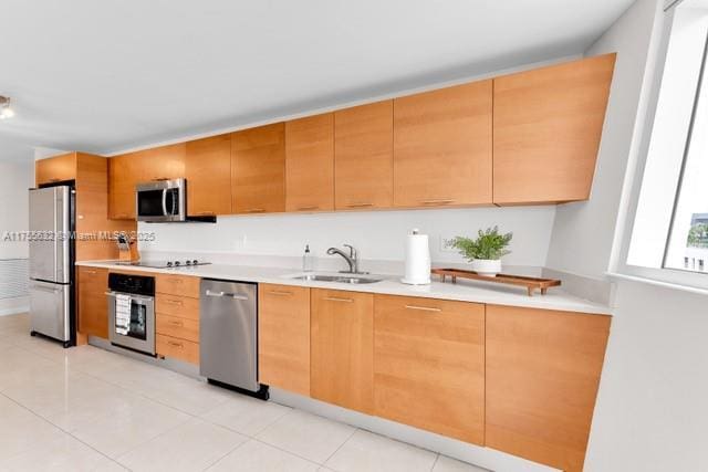 kitchen featuring light tile patterned floors, stainless steel appliances, a sink, and light countertops
