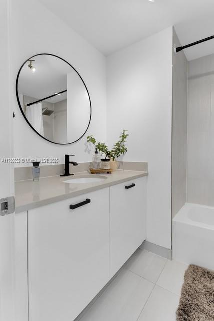 bathroom featuring washtub / shower combination, tile patterned flooring, and vanity