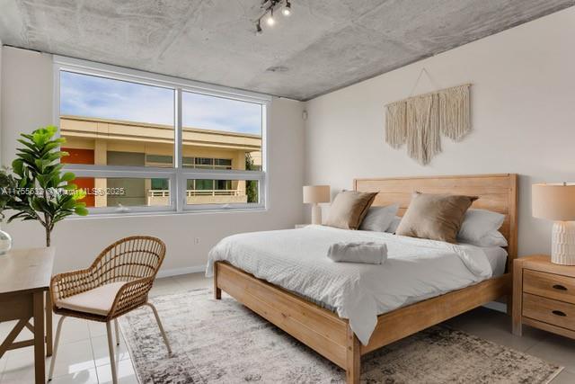 tiled bedroom with multiple windows and track lighting