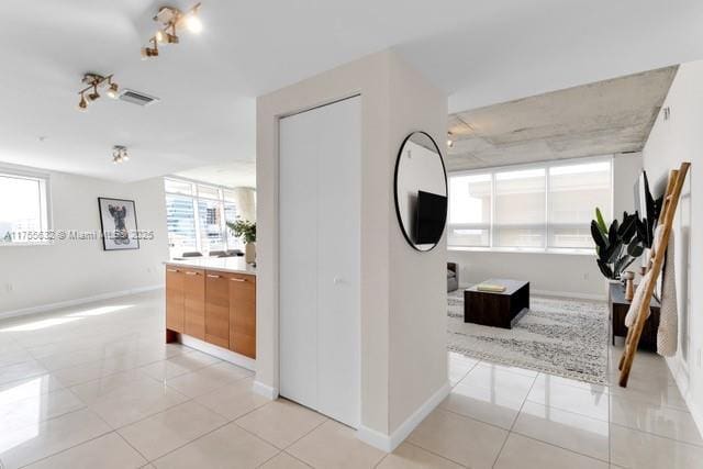 corridor with light tile patterned flooring, visible vents, and baseboards