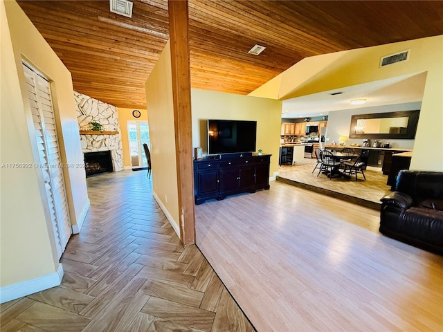 living room featuring vaulted ceiling, visible vents, a fireplace, and baseboards