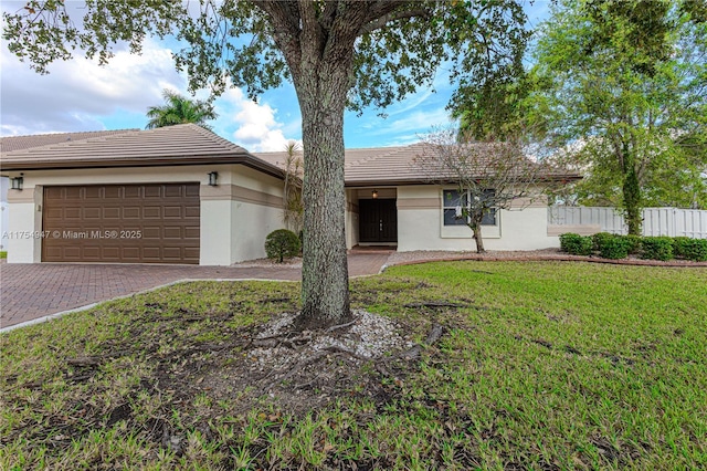 single story home featuring decorative driveway, stucco siding, an attached garage, a front yard, and fence