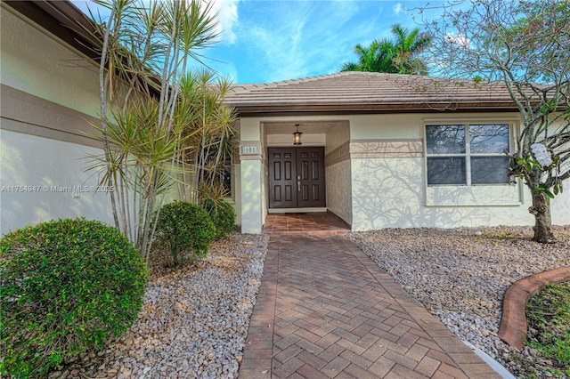 doorway to property featuring a tile roof and stucco siding