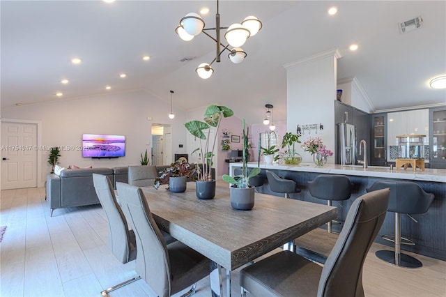 dining room featuring light wood finished floors, visible vents, ornamental molding, and vaulted ceiling