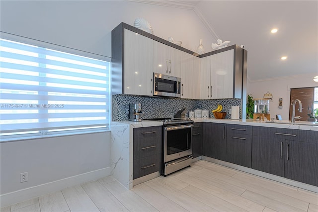 kitchen with stainless steel appliances, decorative backsplash, a sink, and crown molding