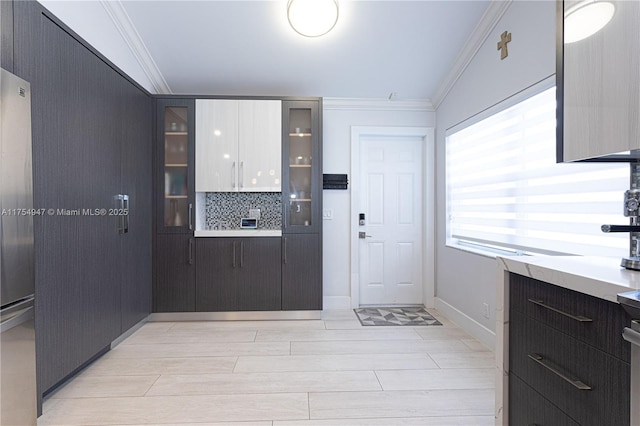 kitchen featuring crown molding, light countertops, backsplash, glass insert cabinets, and modern cabinets