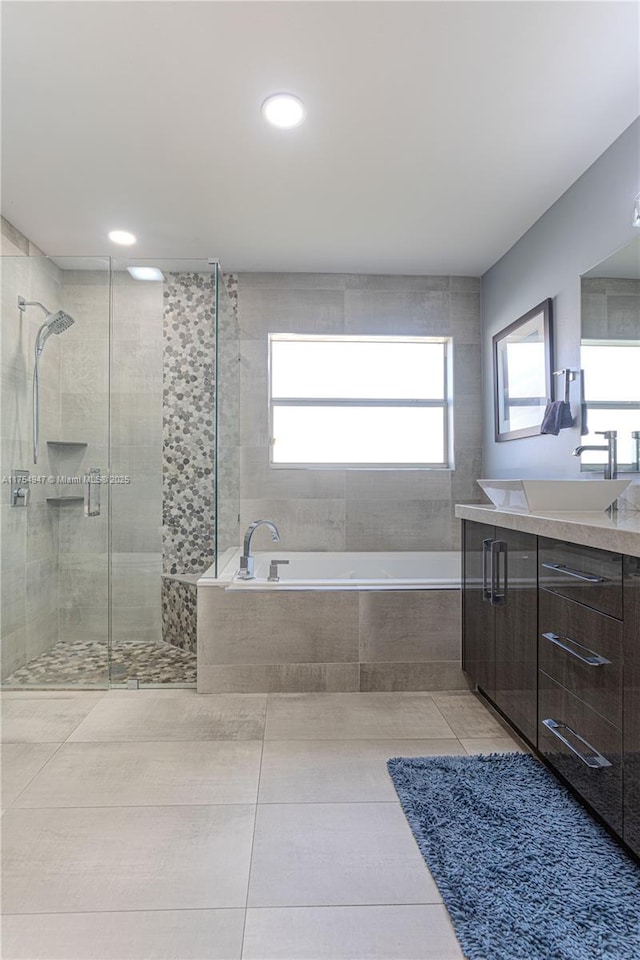 bathroom featuring a stall shower, tile patterned flooring, vanity, and a bath