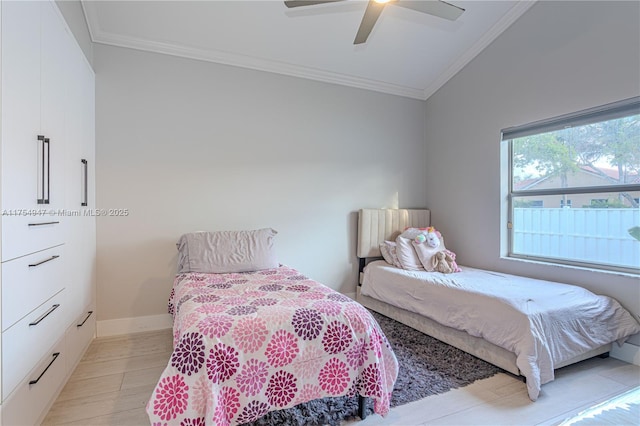 bedroom with light wood finished floors, ornamental molding, a ceiling fan, and baseboards