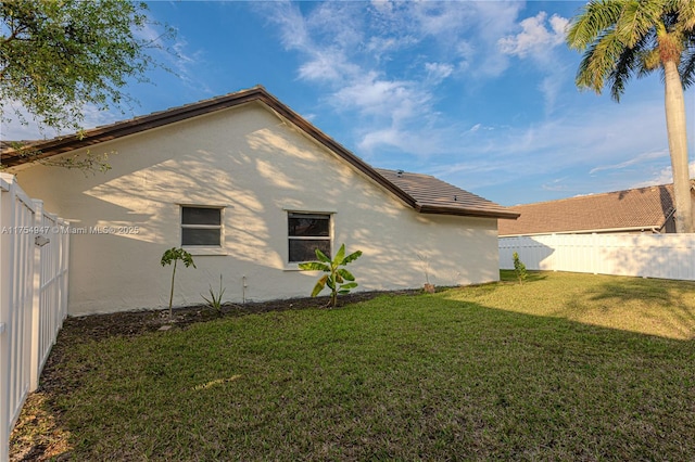 exterior space featuring a fenced backyard, a lawn, and stucco siding