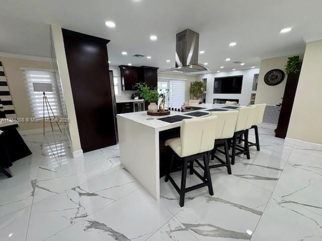 kitchen with marble finish floor, crown molding, a breakfast bar area, a spacious island, and recessed lighting