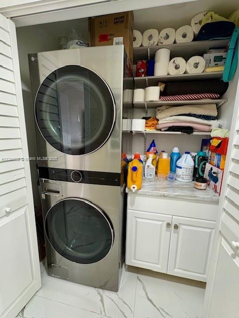 clothes washing area with stacked washer and dryer and cabinet space