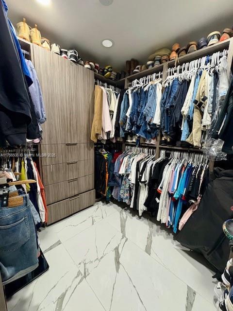 walk in closet featuring marble finish floor