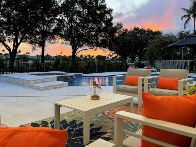 pool at dusk with a patio area, an outdoor pool, outdoor lounge area, and fence