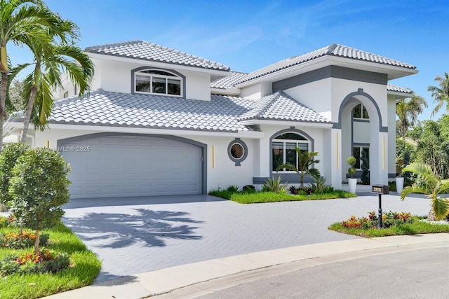 mediterranean / spanish-style home featuring driveway, stucco siding, a garage, and a tiled roof