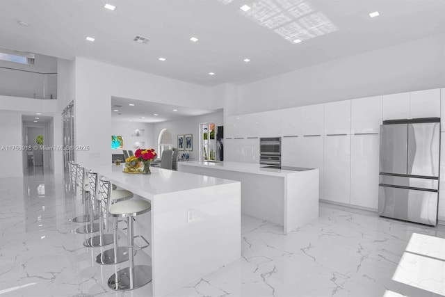 2578 NW 63rd Ln, Boca Raton, FL 33496 - kitchen with light countertops, appliances with stainless steel finishes, white cabinets, modern cabinets, and a kitchen breakfast bar