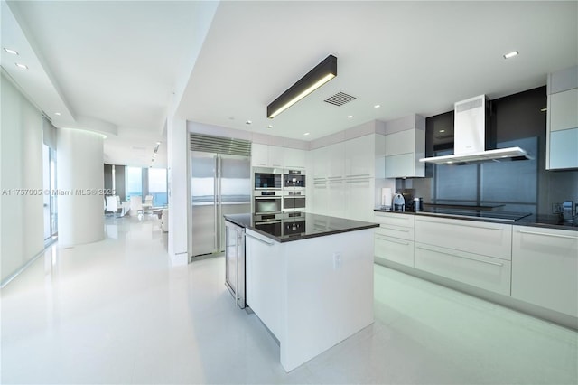 kitchen with black electric stovetop, visible vents, stainless steel built in fridge, wall chimney exhaust hood, and modern cabinets