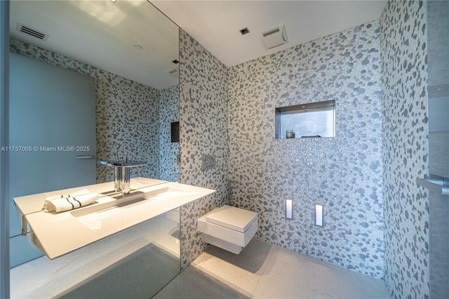 bathroom with toilet, visible vents, and tile walls