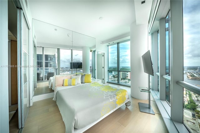 bedroom featuring a wall of windows, access to outside, and wood finished floors