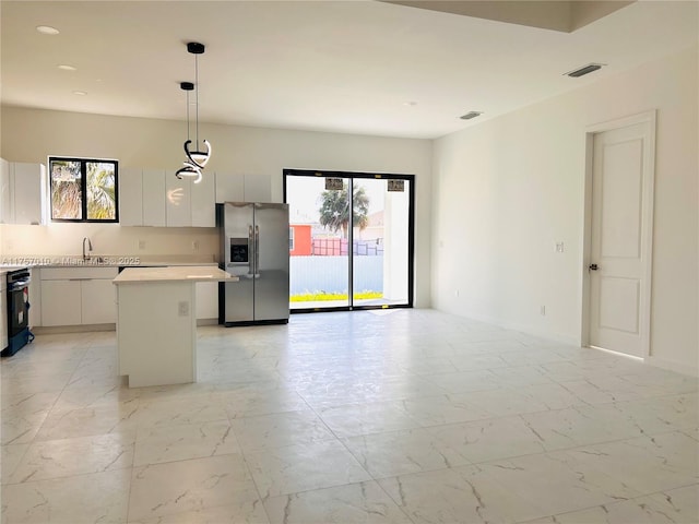 kitchen featuring stainless steel fridge, a kitchen island, hanging light fixtures, marble finish floor, and a sink