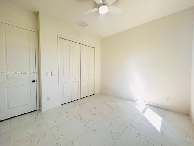 unfurnished bedroom featuring marble finish floor, a closet, visible vents, a ceiling fan, and baseboards