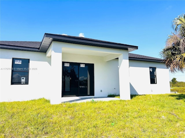 back of property featuring a yard and stucco siding