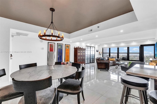 dining room featuring a raised ceiling, visible vents, and a notable chandelier