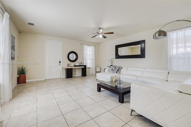 living area featuring light tile patterned floors, baseboards, visible vents, and ceiling fan