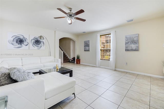 living area with arched walkways, visible vents, a ceiling fan, baseboards, and stairway