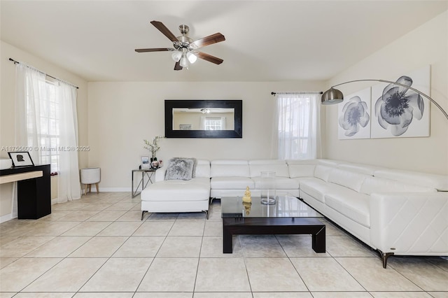 living room with ceiling fan, baseboards, and light tile patterned flooring