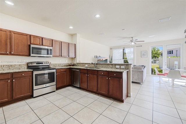 kitchen with light tile patterned floors, recessed lighting, appliances with stainless steel finishes, open floor plan, and a peninsula