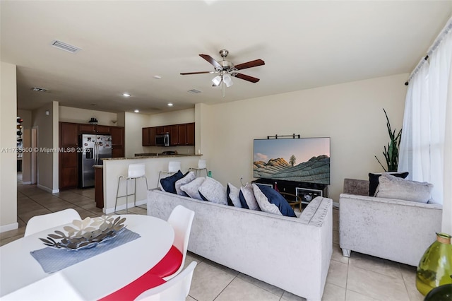 living room with light tile patterned floors, visible vents, and a ceiling fan