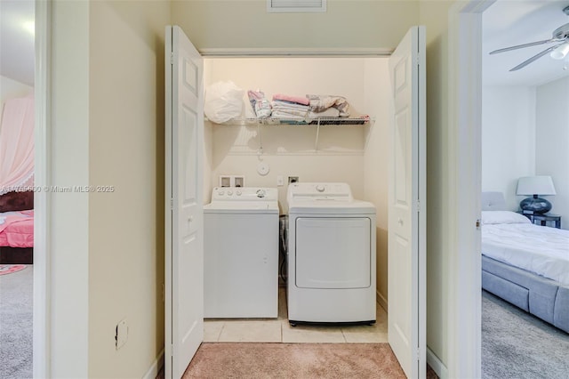 laundry area with washer and clothes dryer, light colored carpet, light tile patterned flooring, ceiling fan, and laundry area