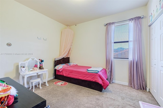 carpeted bedroom with a closet and baseboards