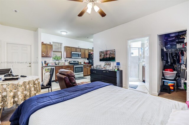 bedroom featuring connected bathroom, freestanding refrigerator, and ceiling fan